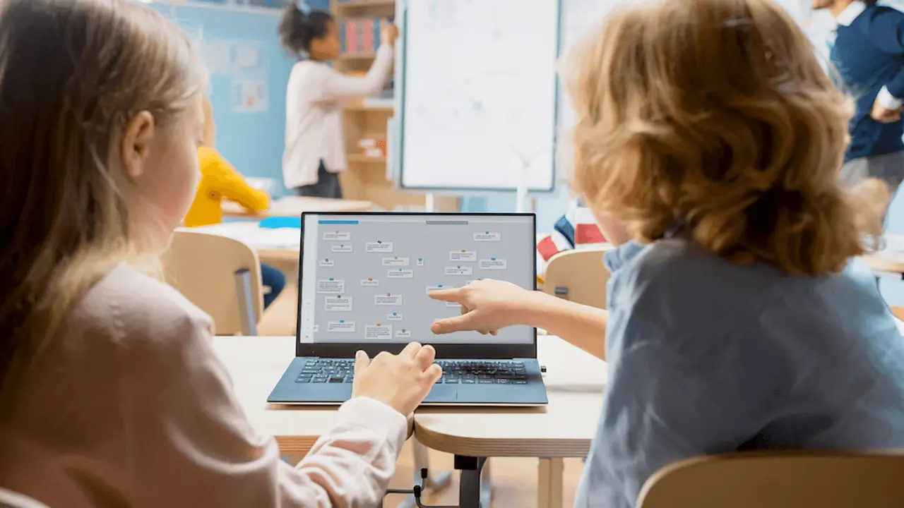 Uczniowie wspólnie analizują materiał edukacyjny na laptopie.